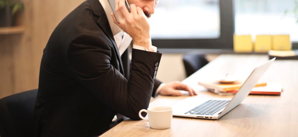 man having a phone call in front of a laptop